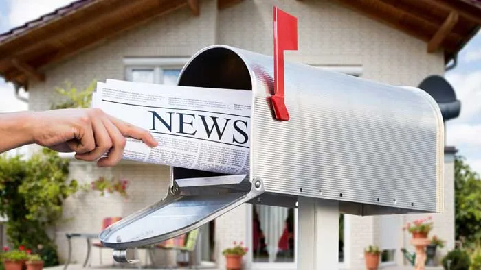Someone putting a newspaper in the mailbox.