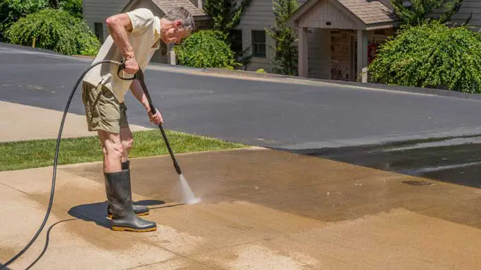 A man power washes his driveway.